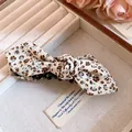 Détail d'une pince à cheveux vintage avec un nœud en tissu floral dans une boîte à bijoux - Pince Torsadée - Blanc et Marron Floral