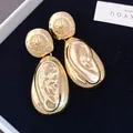 Close-up of elegant golden water drop earrings featuring a unique wrinkled lava texture design - Gold