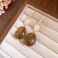 Macro view of vintage resin drop earrings with marble textures and gold bar accents - White-Coffee