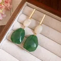 Close-up of vintage resin geometric drop earrings with green and white pendants in a box - White-Green