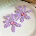 Detailed macro view of purple wrinkled flower earrings featuring pink beaded centers. - Ruffled Flowers / Purple