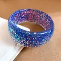 Primo piano di un bracciale in resina blu con scaglie di glitter olografici - Blu scuro