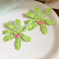 Detail view of lime green flower earrings with wavy petals and pink center beads. - Ruffled Flowers / Green