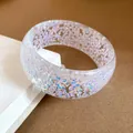 Dettaglio macro di un bracciale in resina iridescente con scaglie colorate. - Bianco