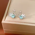 Detailed macro shot of silver swan stud earrings featuring a light blue cushion-cut crystal - Small Swan (Blue Main Stone) / Silver/Blue