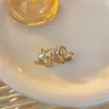 Close-up of French luxury twisted heart stud earrings with sparkling baguette zircons - Gold