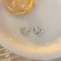 Detailed view of silver heart stud earrings with twisted design and zircon inlay - Silver