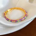 Gros plan d'un bracelet doré de style néo-chinois avec motif floral en émail violet - Or-Vert-Violet