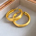 Macro view of matte brushed gold hoop earrings presented in a luxury velvet jewelry box - Silver Earring Post Style / Brushed Gold