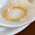 Gros plan d'un bracelet fleuri en émail doré avec design rose et bleu et cristaux - Or, Rose et Cyan