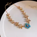 Primo piano di collana a fiori dorata vintage con dettaglio in smalto blu - Collana / Oro-Blu