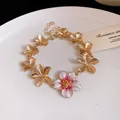 Dettaglio di bracciale vintage a fiori dorati con inserto centrale in smalto - Bracciale / Oro-Rosa