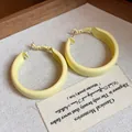 Close-up of matte yellow spray painted hoop earrings with silver pins - Large / Yellow