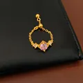 Gros plan d'une élégante bague à chaîne réglable avec un zircon carré rose clair en vedette - Bague Chaîne Réglable / Base Dorée avec Pierre Rose