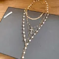 Close-up of multi-layered gold necklace with pearls and rhinestone cross pendant - Gold