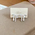Close-up view of elegant silver bow stud earrings with pearl detail on display card - Bowknot Style (1#)