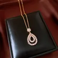 Detail shot of elegant vintage teardrop CZ pendant necklace on black gift box display - Gold