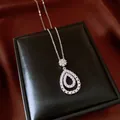 Macro detail of a vintage pear-shaped zircon pendant necklace on a black leather box - Silver