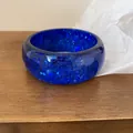 Detailed macro view of a chunky blue resin bangle featuring sparkling blue sequins - Blue