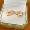 Macro view of gold-tone star-shaped ear clips with sparkling zircon inlays in a gift box - Ear Clip (Pair) / Gold