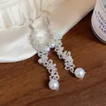 Detail shot of elegant handmade beaded long dangle earrings with white faux pearls - Hook Style / White