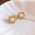 Close-up of French vintage hollow flower stud earrings with elegant zircon and pearls. - Gold