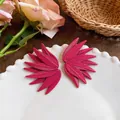 Close-up of magenta leaf-patterned stud earrings with textured wing design on a white plate. - Rose Red