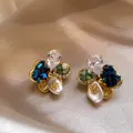 Détail en gros plan de boucles d'oreilles fleurs vintage avec cristaux et perles - Or-Bleu-Vert