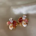 Gros plan détaillé de boucles d'oreilles vintage fleurs en verre coloré sur du satin - Or-Rouge-Rose