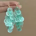 Close-up detail of mint green translucent petal-like disc tassel earrings with golden stud tops. - Overlapping Sheet Tassel (29#)