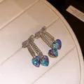Macro view of sparkling bow tassel earrings with iridescent blue heart crystals - Blue