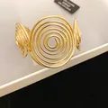Macro view of a gold-toned cuff bracelet with an exaggerated spiral design motif - Multi-layer Spiral Style / Gold