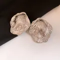 Detailed view of textured silver leaf earrings with intricate pleated metal design - Silver