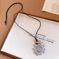 Close-up of a silver flower pendant necklace with an orange bead on a black cord - Flower Style (6269928895174) / Silver