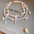 Dettaglio squisito della collana multistrato di perle e conchiglie con accenti di catena d'oro - Collana di Perle a Più Strati / Oro-Bianco