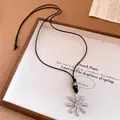 Close-up of silver flower pendant with fishbone texture and beaded black cord - Pleated Flower Style (6269928895173) / Silver
