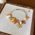 Detailaufnahme von handgemachtem Urlaubsarmband mit Muscheln und goldenem Seestern - Armband-Gold-Mehrfarbig