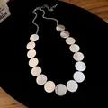 Detailed view of a silver brushed metal round disc necklace on a black background - Necklace - Silver