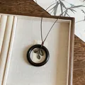 Close-up of Neo-Chinese style necklace with wooden ring and bronze leaf charms. - Round Pendant / Coffee and Gold