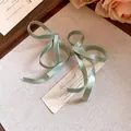 Primo piano dettagliato di eleganti orecchini a fiocco in nastro di seta verde vintage - Verde