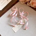 Vista macro dei dettagli di orecchini a fiocco in nastro di seta rosa su carta. - Rosa