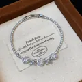 Close-up of elegant silver-toned CZ bracelet with rhombus and flower charms in a gift box - Silver-White