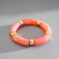 Detailed view of an orange marbled acrylic stretch bracelet with gold-tone spacers - Pink