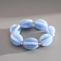 Close-up of blue swirled acrylic beads with gold spacers on an elastic bracelet. - Blue
