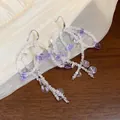 Detailed view of elegant purple glass beaded bow-tassel drop earrings on sheer fabric. - Purple