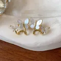 Macro view showing 14k gold plated butterfly earrings with zircon and shell wings - Intertwined Double Butterfly (9#) / Gold