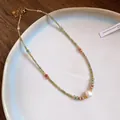 Close-up of vintage beaded necklace with colorful stones and a central white pearl - Baroque Pearl Accents / Gold-Green-Pearl