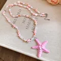 Dettaglio di una collana a due strati con perline e stelle marine rosa per le vacanze estive. - Rosa