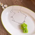 Close-up view of a cute green plush bear necklace decorated with pearls and zircon charms - Pearl Chain Bow Style