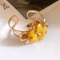 Detailed view of a vintage gold metal cuff bracelet with yellow enamel flower petals. - Open Design / Yellow